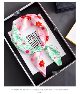 Detailed view of color-block floral silk scarf with daisies and roses on a tray
