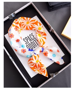 Detailed close-up of orange floral square silk scarf with white daisy prints