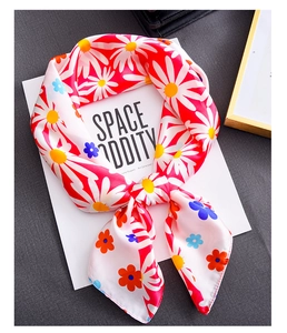 Detail shot of a silky floral square scarf featuring vibrant daisies and smooth texture