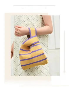 Détail d'un sac noué en tricot rayé jaune et violet porté avec une robe à pois