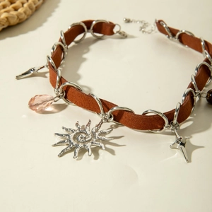 Detail of bohemian suede choker featuring silver sun, star and pink crystal pendants