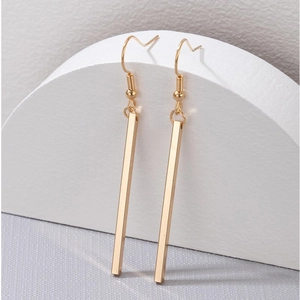Macro view of gold geometric long bar drop earrings with polished minimalist finish