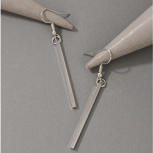 Minimalist geometric bar earrings with silver drop hooks on a gray display stand