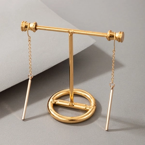 Close-up of minimalist gold geometric bar earrings on a metal display stand