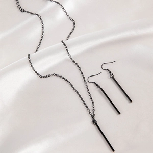 Detailed view of minimalist black geometric bar necklace and earrings on silk background