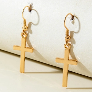 Close-up of polished gold-plated metal cross earrings with hook design on display
