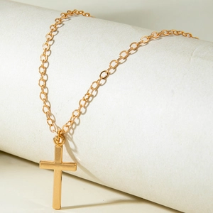 Close-up of a polished gold cross necklace on a delicate chain over a white display