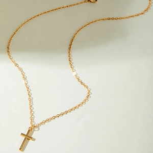 Detailed view of a minimalist golden cross pendant necklace with a polished metal finish