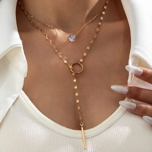 Close-up of double-layer gold necklace with heart zircon and elegant metal bar tassel