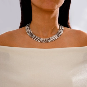 Makroaufnahme einer breiten, silbernen Gliederkette am Model in einem weißen Kleid