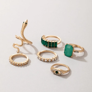Dettaglio di anelli vintage dorati con pietre verde smeraldo e design a serpente