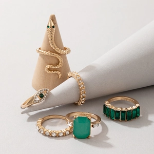 Dettaglio del set di anelli dorati con pietre verde smeraldo e design a serpente