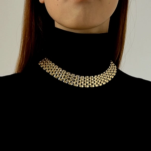 Punk style chunky gold woven choker necklace worn on a black sweater for a bold look