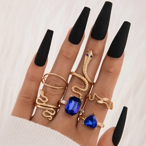 Dettaglio del set di anelli a serpente dorati con gemme blu scuro sulla mano