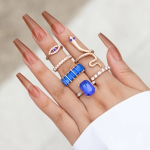 Set di 6 anelli dorati con gemme blu e motivo a serpente, indossati sulle dita