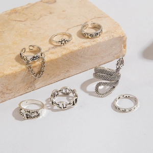 Detailed view of 7-piece vintage snake and floral silver rings on marble stone display