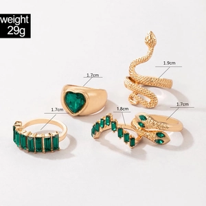 Dettaglio del set di cinque anelli dorati con serpente, cuore e gemma verde scuro