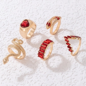 Dettaglio di un set di 5 anelli dorati con serpenti e pietre preziose rosse a cuore