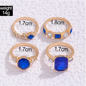 Dettaglio di quattro anelli dorati con pietre blu e specifiche sulle dimensioni