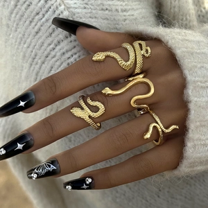 Set of four vintage gold snake-shaped wrap rings with textured scales on a female hand