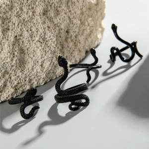 Macro shot of four black snake rings with scale texture on a natural stone background