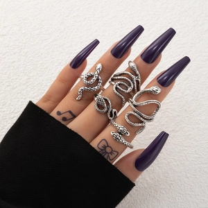 Close-up of four vintage silver snake rings with detailed scale texture on a hand