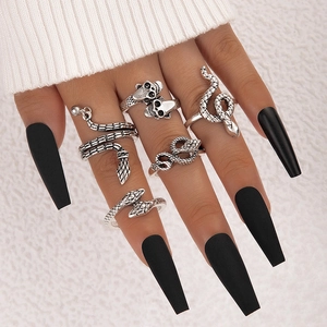 Detail of vintage silver snake rings and skull ring set worn on hand with black nails