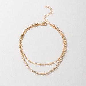 Close-up of double layer gold anklet featuring multi-color rhinestones and lobster clasp