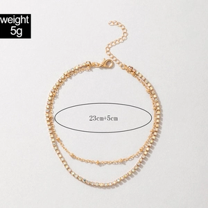 Close-up of double-layer gold anklet with small gold beads and colorful crystal rhinestones