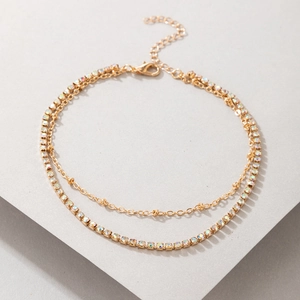 Detail of a double-layered gold anklet with sparkling rhinestones and delicate beads