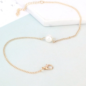 Detail of minimalist gold anklet featuring a white pearl bead and adjustable lobster clasp