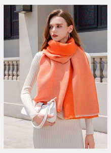 Close-up of vibrant orange pleated cashmere-like scarf with elegant wrinkled texture for women