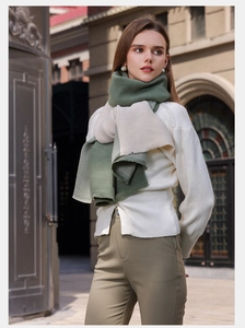 Detail of elegant pleated cashmere-like scarf in dark green and beige worn by model