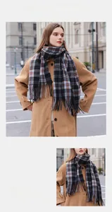 Détail d'une écharpe à carreaux effet cachemire avec de longues franges en noir, marron et bleu