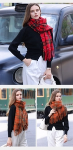 Détail d'une écharpe à carreaux rouge et orange avec de longues franges en style urbain