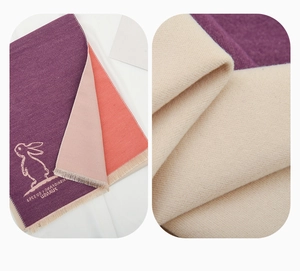 Detail of warm winter neck warmer with cute rabbit print and soft tassel edges