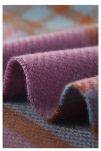 Macro shot of soft plaid cashmere-like fabric showing colorful knitted texture and fringe