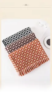 Flat lay of soft plaid scarves in multiple colors with tassels and cozy coffee cup decor