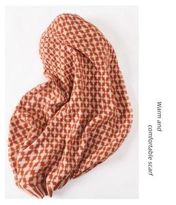 Detailed close-up of orange and beige cross-knit grid texture on a warm winter scarf