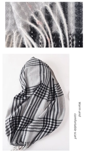 Detail showing the gray and beige plaid knit texture and tassel fringe of the winter scarf