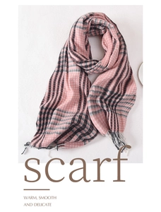 Detail of pink and navy plaid scarf featuring twill texture and long tassel fringe trim