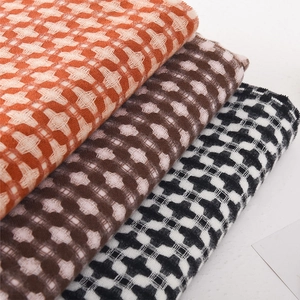 Plaid knitted scarf in orange, coffee, and black tones with textured grid pattern