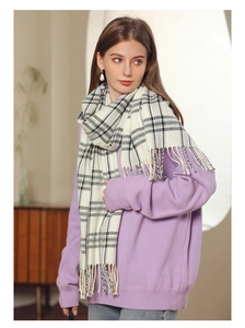 Detail of soft cream scarf with blue plaid patterns and elegant fringe tassels