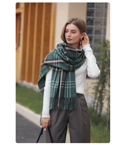Close-up of classic dark green plaid scarf with soft fringe trim and thick warm fabric
