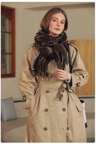 Detailed close-up of dark brown plaid scarf with tassels and classic khaki trench coat
