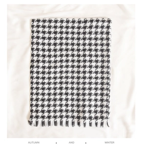 Detail eines klassischen schwarz-weißen Hahnentrittschals mit Fransen und Strickstruktur