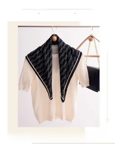 Detail view of a black and white geometric silk scarf with letter patterns on a hanger