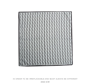 Detail of square silk scarf featuring silver-white fabric with black repeating B patterns