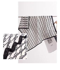 Macro detail of monogram pattern silk scarf with elegant black border and soft fabric texture