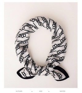 Close-up of a minimalist black and white silk scarf with abstract linear patterns